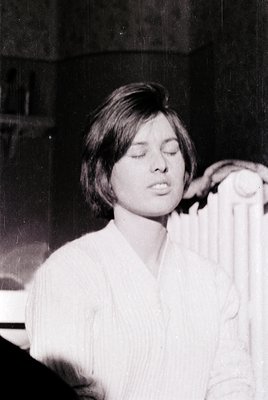 Black-and-white portrait of a woman with short, neatly styled hair, dressed in a high-neck blouse. Her closed eyes and relaxe...