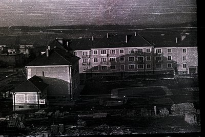 Aerial view of a mid-20th century Soviet-era apartment complex with utilitarian Brutalist architecture. Three-story block fea...
