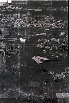 Aerial view of a densely packed industrial site with stacked wooden planks and lumber, likely a sawmill or timber yard. The l...