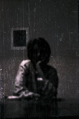 Silhouetted figure seated on a ledge, back to camera, in a dimly lit interior with vertical light streaks. Possible vintage o...