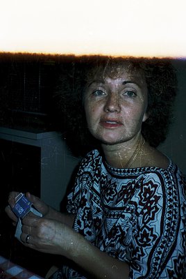 Portrait of a woman in a patterned blouse, holding a vintage camera with a "Kodak" label. Soft evening light filters through ...