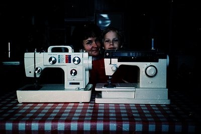 Vintage sewing machines (likely Singer Model 99K) flanked by two individuals in a dimly lit indoor setting, possibly a worksh...