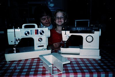 Vintage Singer sewing machines (Model 404 and 405) displayed on a checkered tablecloth, likely mid-20th century. Two individu...