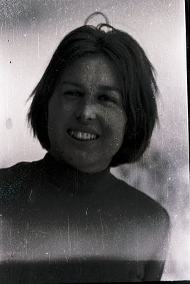Vintage black-and-white portrait of a young woman with short, layered hair and a warm smile. She wears a turtleneck sweater a...