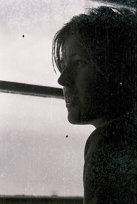 Silhouetted profile of a person under a showerhead, captured in monochrome. Minimalist bathroom interior with white walls and...