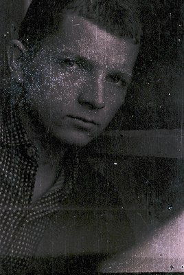 Vintage black-and-white portrait with heavy speckled film damage, likely from aged or damaged photographic paper. Subject wea...