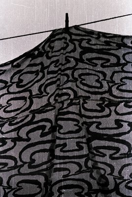 Close-up of a vintage patterned umbrella with intricate cloud-like designs in black-and-white. The fabric appears aged, sugge...