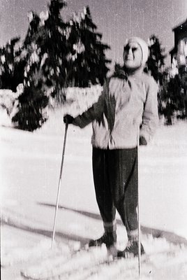 Mid-20th century skier in classic alpine gear—wool sweater, knit cap, and ski poles—on groomed snow. Snow-laden evergreens an...