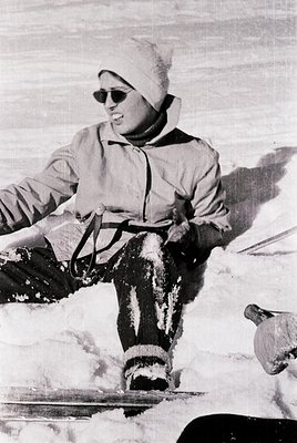 Vintage skier in mid-descend with retro sunglasses, white knit cap, and insulated gear. Snow-covered slopes and ski poles sug...