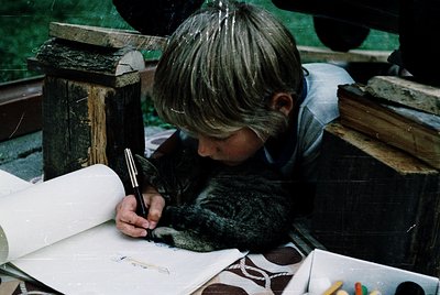 Vintage black-and-white photo of a child intently sketching outdoors, seated on a wooden bench. Open sketchbook rests on knee...