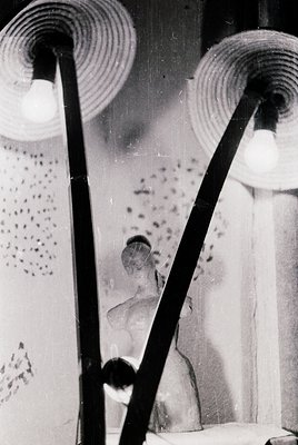 Vintage black-and-white photo of two vintage wall-mounted lamps with spiral metal shades, casting soft light. Reflections rev...