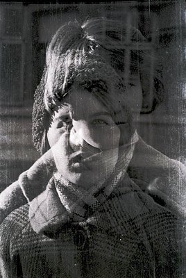 Vintage black-and-white portrait with layered transparency effect, revealing a woman with short, textured hair and a neutral ...