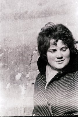Vintage black-and-white portrait of a woman with short, voluminous hair in a side-parted style, wearing a striped sweater. Th...