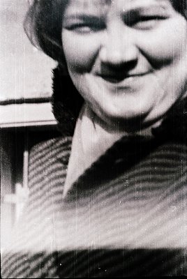 Portrait of a smiling individual in a striped sweater, mid-20th century style. Soft focus and vintage grain suggest a persona...