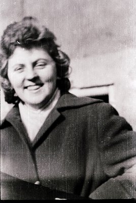Black-and-white portrait of a woman with short, voluminous hair styled in a 1950s-60s bob, wearing a tailored blazer with a b...