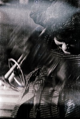 Vintage black-and-white close-up of a person adjusting a crossbody strap, likely a camera or bag. Distressed film grain and s...
