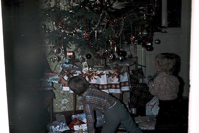Vintage holiday scene featuring a family wrapping gifts under a decorated Christmas tree adorned with glass ornaments and tin...