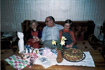 Mid-20th century family portrait (likely 1960s–1970s) featuring a man and two children seated on a vintage sofa. Surrounding ...