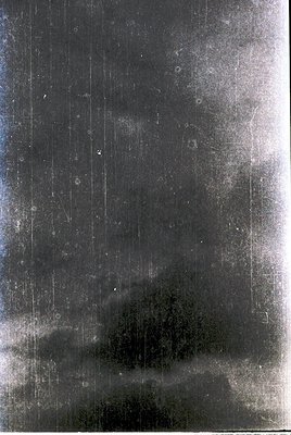 Vintage sepia-toned photograph of a dense, vertical industrial structure with visible rivets and weathered metal. Likely a fa...