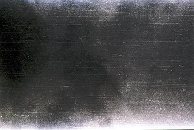 Vintage black-and-white film strip with visible horizontal scratches and grain, likely from a 35mm camera. The degraded textu...