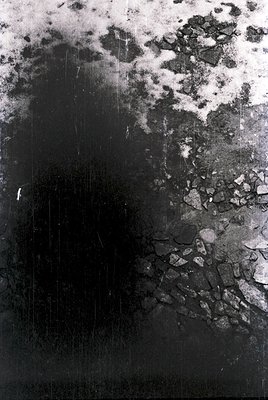 Vintage black-and-white photograph of a cracked, weathered wall with peeling paint and exposed texture, likely concrete or pl...