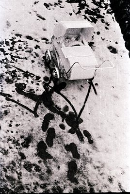 Vintage snowmobile with sidecar traversing a snow-covered trail, likely in a remote or rural area. The vehicle’s design sugge...