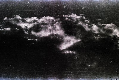Vintage black-and-white aerial view of dense cloud formations over flat terrain, likely mid-20th century. High-contrast skies...