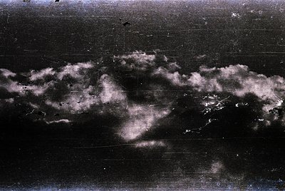 Vintage monochrome sky shot with dramatic, billowing clouds against a dark horizon. Likely captured on film with high-contras...