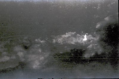 Vintage aerial view of dense forest with misty, low-hanging clouds obscuring visibility. Tree canopy appears uniform, suggest...