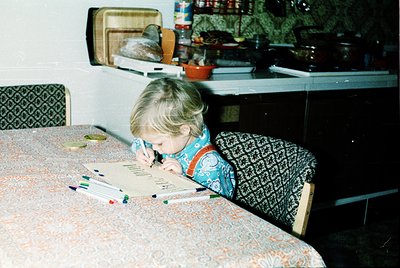 Child engrossed in coloring at a kitchen table, surrounded by mid-century kitchenware: vintage trays, ceramic pots, and patte...