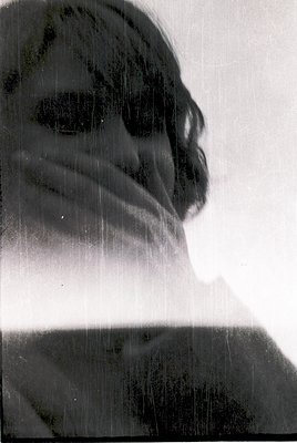 Black-and-white portrait of a person with wet hair and sunglasses, captured mid-motion. The dynamic water droplets create a b...