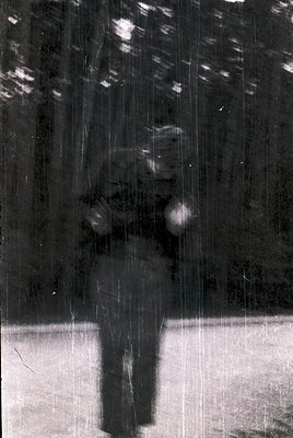 Silhouette of a figure skating on an ice rink, captured through a rain-streaked window. The motion blur suggests speed and fl...