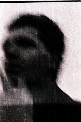 Silhouette of a person in profile, backlit against a textured wall. Likely mid-20th century due to monochrome and grainy qual...