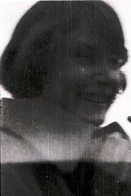 Vintage monochrome portrait with heavy grain and light damage, depicting a woman in profile. She wears a rounded cap and a hi...