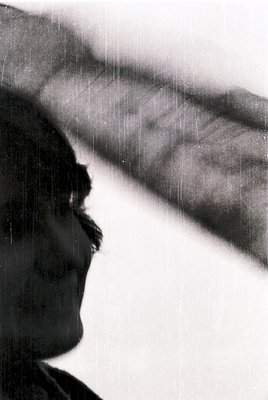Silhouette of a person with a mustache and short hair, facing upward under a rain-soaked awning. The vertical rain streaks cr...