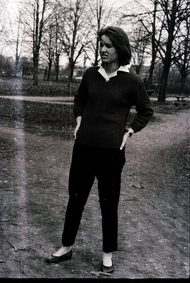 Black-and-white portrait of a woman in mid-20th-century athletic wear: fitted V-neck sweater and matching pants, paired with ...