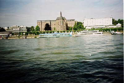 Historic waterfront scene featuring a grand neoclassical building with a central tower and symmetrical façade, likely a gover...
