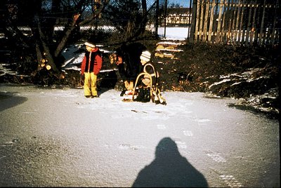 Winter rescue operation in progress: two emergency responders in full gear—yellow pants, red jackets, helmets—assist a fallen...