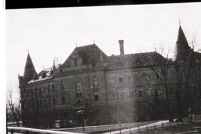 Historic stone building with Gothic Revival elements—steeples, arched windows, and decorative brickwork. Snow covers rooftops...