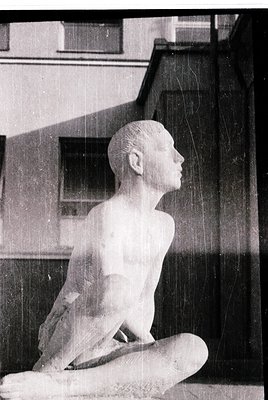 Classic marble sculpture of a seated child, likely from the 20th century. The figure’s serene pose and smooth finish suggest ...