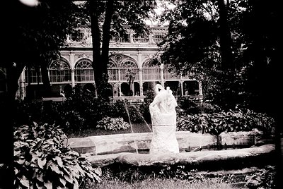 Vintage black-and-white photo of a grand seaside villa with ornate balconies and arched windows, surrounded by lush greenery....