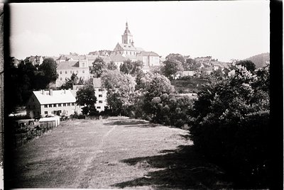 Black-and-white aerial view of a European town with a prominent church spire dominating the skyline. Mid-20th century archite...