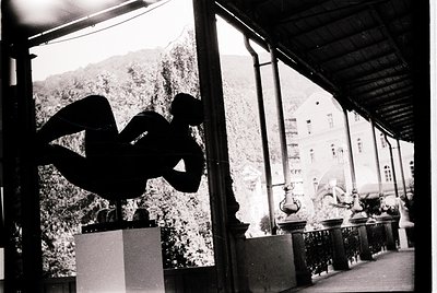 A striking black-and-white sculpture of intertwined human figures dominates a covered colonnade, framed by classical columns ...