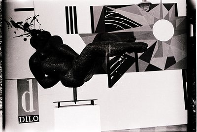 Mid-century modern sculpture by Dilo, featuring abstract human form in dynamic pose. Geometric backdrop with bold lines, circ...
