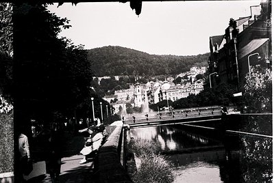 Black-and-white street scene featuring a canal flanked by pedestrian pathways. Mid-20th century urban architecture with Art D...