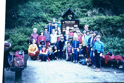Group photo at a mountain trailhead signpost reading *"Dolina plodnej práce"* (Valley of Hard Work) in Slovak. Mid-20th centu...