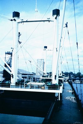 Vintage industrial ship deck with multiple masts, winches, and rigging. Mid-20th century maritime architecture, likely a carg...