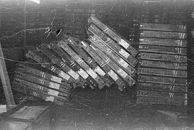 Stacks of rectangular boxes with handwritten numbers and labels. One pile is leaning diagonally to the left, while another st...