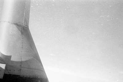 A black and white close-up of a metallic structure, possibly a tower or aircraft part, featuring visible rivets and panel sea...
