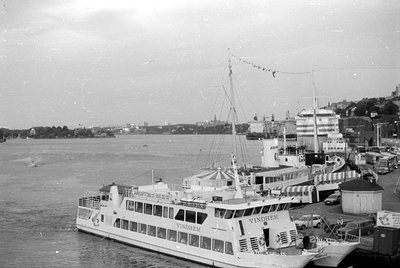 A white passenger boat named 'VINDHEM' is docked at a harbor. The boat features the text 'RÅKAFTON' and a phone number. Other...